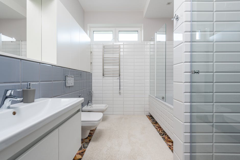 Contemporary empty bathroom with white walls furnished with toilet and bidet and sink