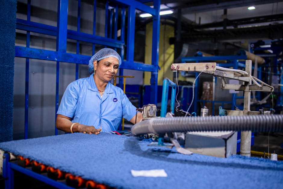 Female factory worker operates textile machinery indoors, showcasing dedication and skill in industrial setting.