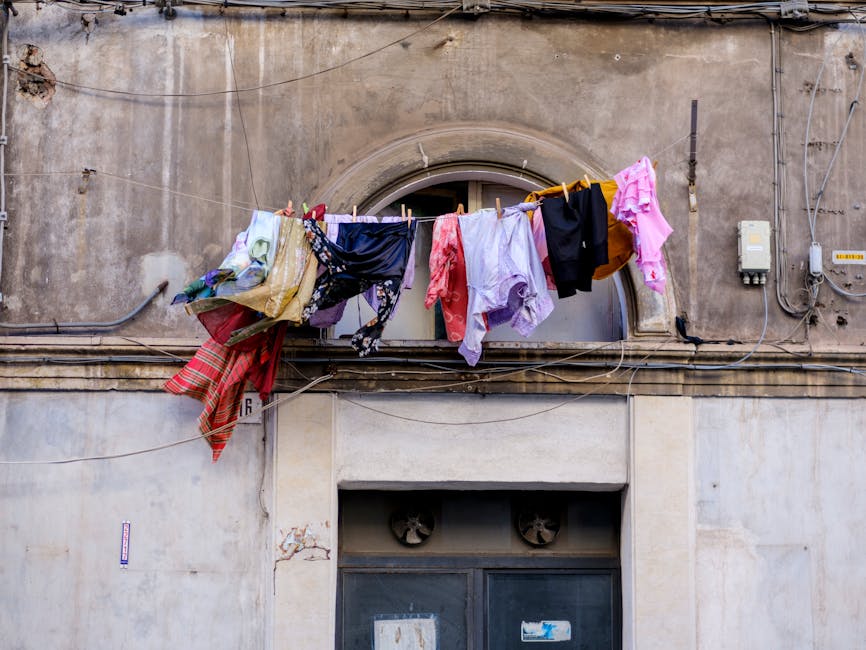 Vibrant clothes hanging on a clothesline against a rustic Sicilian building facade in Catania.