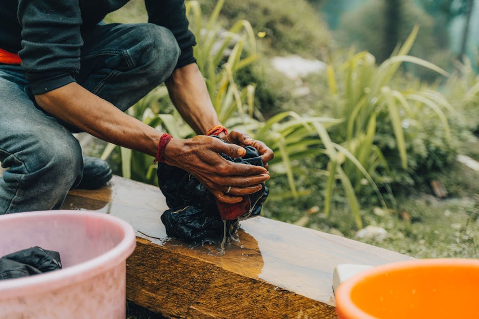 Man washes clothes by hand in an outdoor natural environment. Manual labor and daily routine depicted.