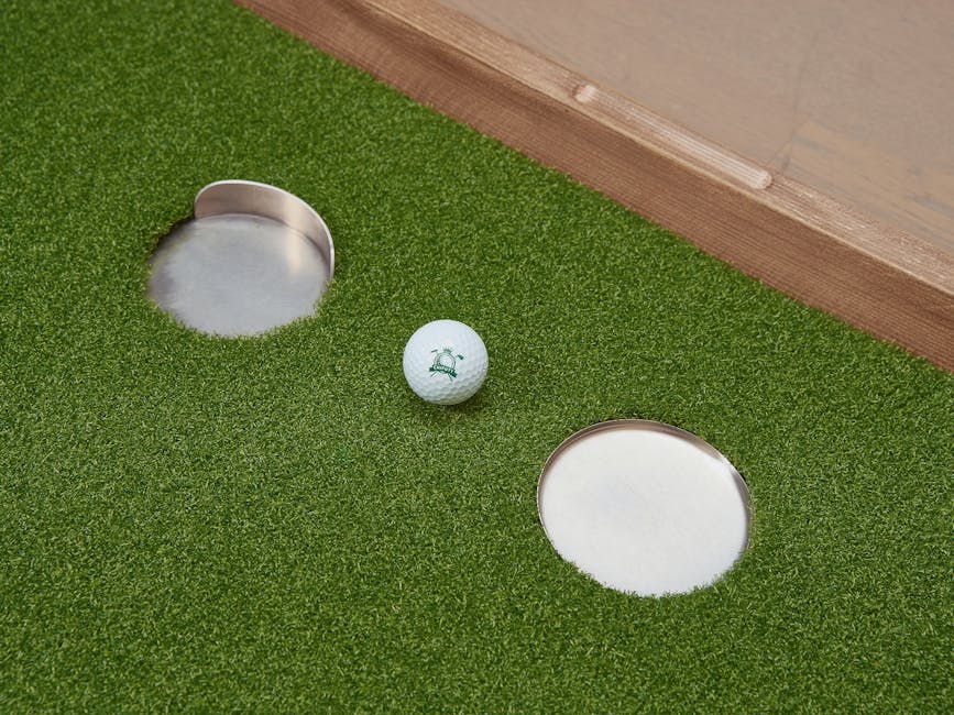 Close-up of an indoor putting green with a golf ball and two holes, perfect for practice.